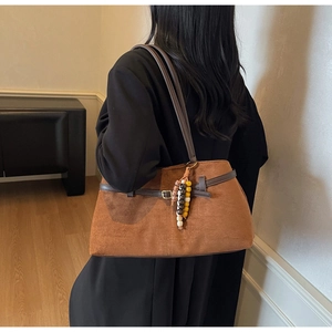 Detail view of brown vintage suede shoulder bag with decorative colorful beads and metal buckle