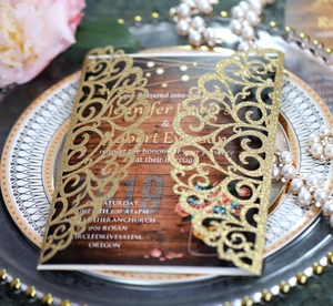 Close-up of laser-cut gold glitter wedding invitation with elegant wood grain texture