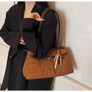 Detail of vintage brown suede tote bag featuring ethnic beads and a slim leather strap