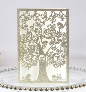 Detailed laser-cut tree of life design on golden glitter paper with bird and owl details
