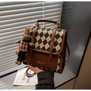 Detailed macro of checkered fabric texture and brown leather flap on the retro crossbody bag