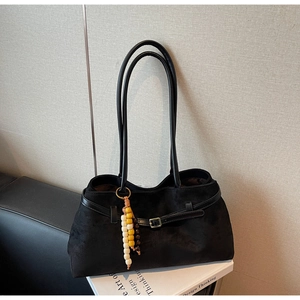 Detail of black suede tote bag with wooden bead pendant and metal buckle decoration