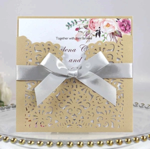 Détail de l'invitation de mariage découpée au laser avec pochette dorée et nœud en soie