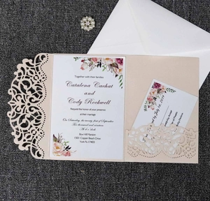 Detailed laser-cut wedding invitation set with floral inserts and a pearl rhinestone charm