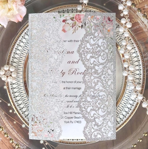 Macro detail of silver glitter laser cut wedding invitation with rose floral inner card