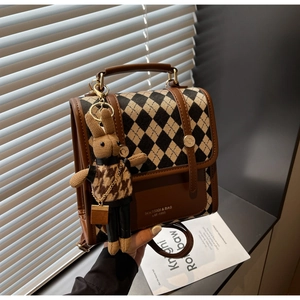 Detail view of retro diamond lattice bag with metal buckle and cute knit bunny charm