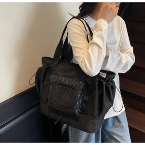 Detail view of black travel bag with diamond texture pocket and side drawstring
