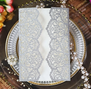 Close-up of laser-cut silver glitter wedding invitation with elegant floral lace details