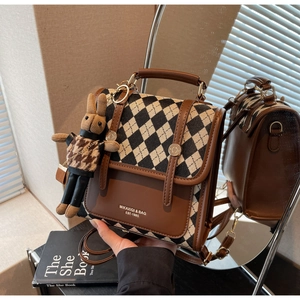 Detail of checkered backpack with brown leather trim and cute rabbit doll charm