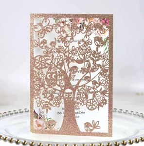 Macro view of rose gold glitter laser-cut tree and bird pattern on festive invitation card