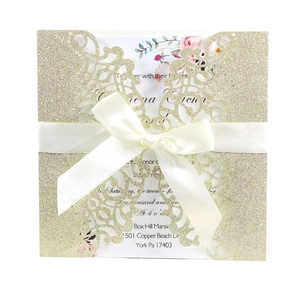 Carte d'invitation dorée pailletée découpée au laser avec nœud blanc et motif floral