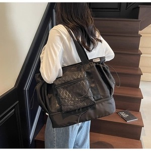 Detail of black travel tote showing drawstring top, quilted pocket, and bottom shoe compartment