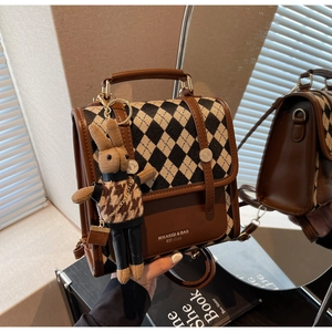 Detail view of brown quilted handbag with a woven rabbit charm and brand logo imprint