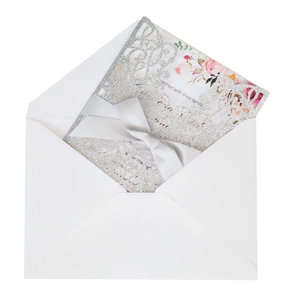 Detail view of laser-cut silver glitter invitation suite with floral insert and ribbon