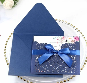 Détail de l'invitation de mariage bleue découpée au laser avec ruban et carte fleurie