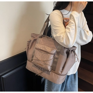 Spacious pink nylon travel bag with dual handles and side drawstring pocket shown on shoulder