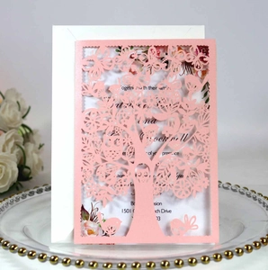 Detail of laser-cut pink tree and bird invitation card on elegant ceramic plate