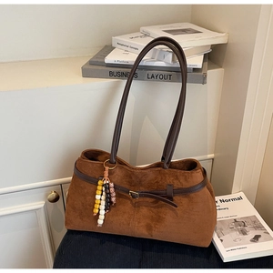Close-up of caramel suede tote bag with brown straps and colorful beaded tassel detail