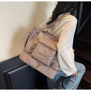 Pink large travel bag shown by model featuring quilted pocket and bottom shoe compartment