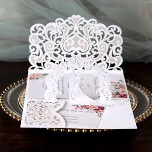 Détail de l'invitation de mariage découpée au laser avec arche blanche et carte fleurie