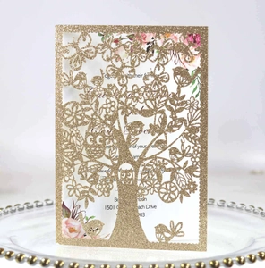 Close-up of glitter gold laser cut tree design wedding invitation with floral insert card