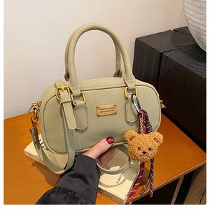 Detail view of olive green bowling bag with matte finish and plush bear charm