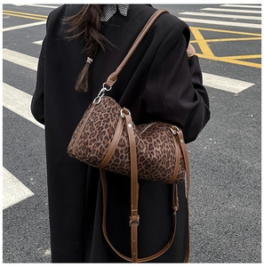 Rear view of a leopard print cylinder shoulder bag worn over a grey coat in the street