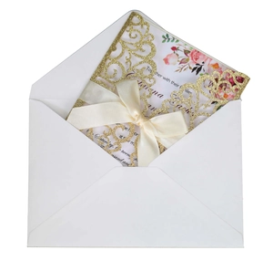 Macro detail of laser-cut glitter wedding invitation with beige satin bow and floral insert