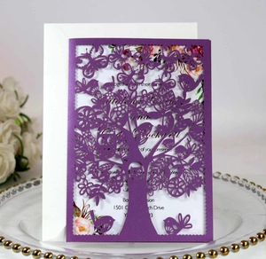 Detail of laser-cut purple invitation featuring tree and bird patterns with a white insert