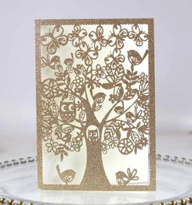 Detailed laser-cut tree and butterfly motifs on glitter paper wedding invitation