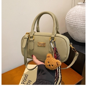 Detail of sage green boston handbag with gold plate and cute brown plush bear charm