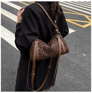 Detail of leopard print crossbody bag with brown leather straps and silver hardware