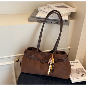 Detail of coffee brown suede tote bag with ethnic beaded charm and long leather strap