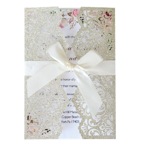 Detailed laser cut champagne gold glitter invitation with satin bow and floral insert