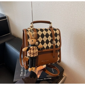 Close-up of retro brown crossbody bag featuring rhombic texture and a cute rabbit charm