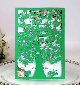 Detail of laser-cut green tree and bird pattern on an elegant invitation card
