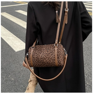 Street style shot of leopard print barrel bag with brown straps and silver zipper