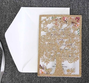 Detail of glitter gold laser-cut invitation card with butterfly and tree patterns
