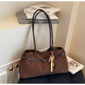 Detailed view of dark brown suede shoulder bag with gold hardware and colorful beaded charm