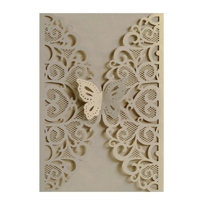 Detail of laser cut champagne gold wedding invitation with intricate butterfly lace pattern