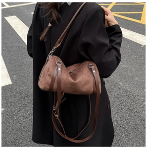 Outdoor shot of a brown frosted leather pillow bag with long shoulder strap on model