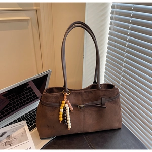 Detailed macro view of the brown suede tote bag with retro beaded charm and hardware
