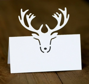 Detailed laser cut white reindeer place card with a blank space on a rustic wooden table
