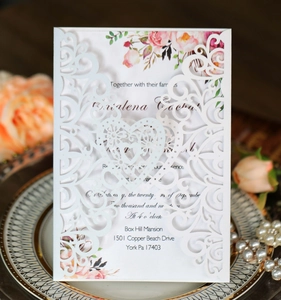 Detail of laser-cut heart wedding invitation with floral insert and pearl decor