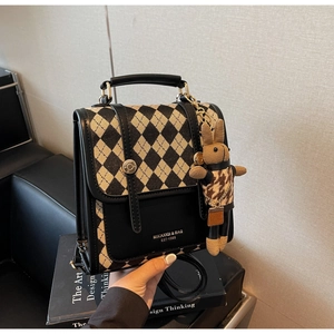 Detail of rhombic canvas handbag with leather trim and cute rabbit plush pendant