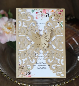 Close-up of laser-cut butterfly invitation with intricate floral lace and gold inner card
