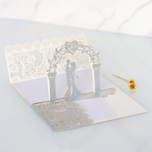 Detail of 3D laser-cut wedding card featuring a glittery silver arch and couple silhouette