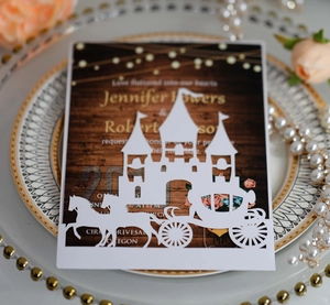 Intricate laser-cut wedding invitation featuring a fairy tale castle and carriage design