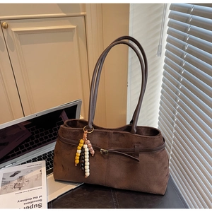Detail of dark brown suede shoulder bag with decorative colorful beaded tassel and leather strap