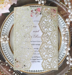 Detail of glitter laser cut wedding invitation with elegant floral card on a ceramic plate